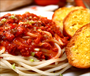 Photo illustration of spaghetti noodles covered with red marinara sauce and three pieces of garlic bread