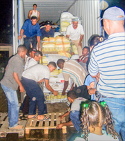 A photo of families at Las Palmas unloading the previous shipping container of supplies they received